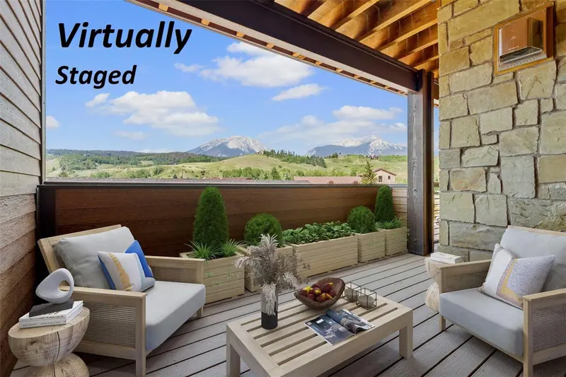 Furnished balcony with seating, a table, and potted plants overlooks mountains and green hills under a blue sky. Text reads Virtually Staged in the top left corner.
