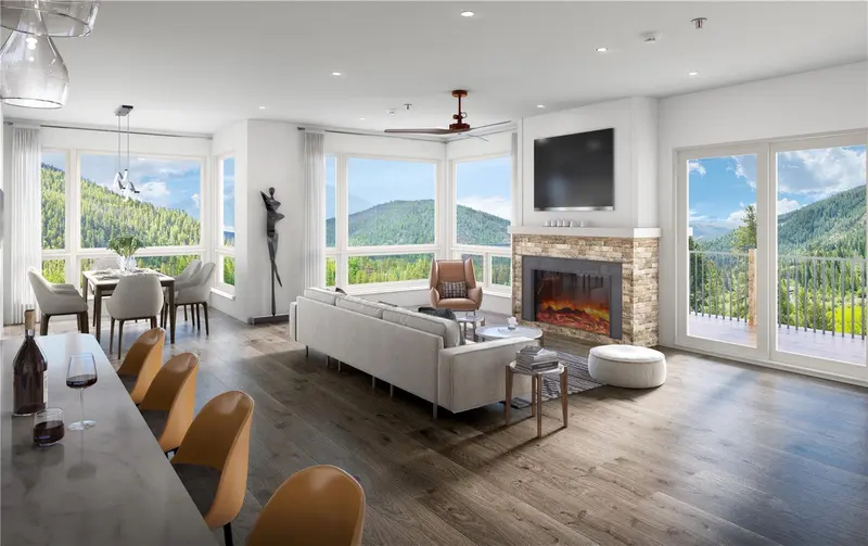 Modern living room with large windows, a beige sofa, dining area, fireplace, TV, and mountain views. Bar stools and a balcony are also visible. The space is bright with natural light and elegant decor.