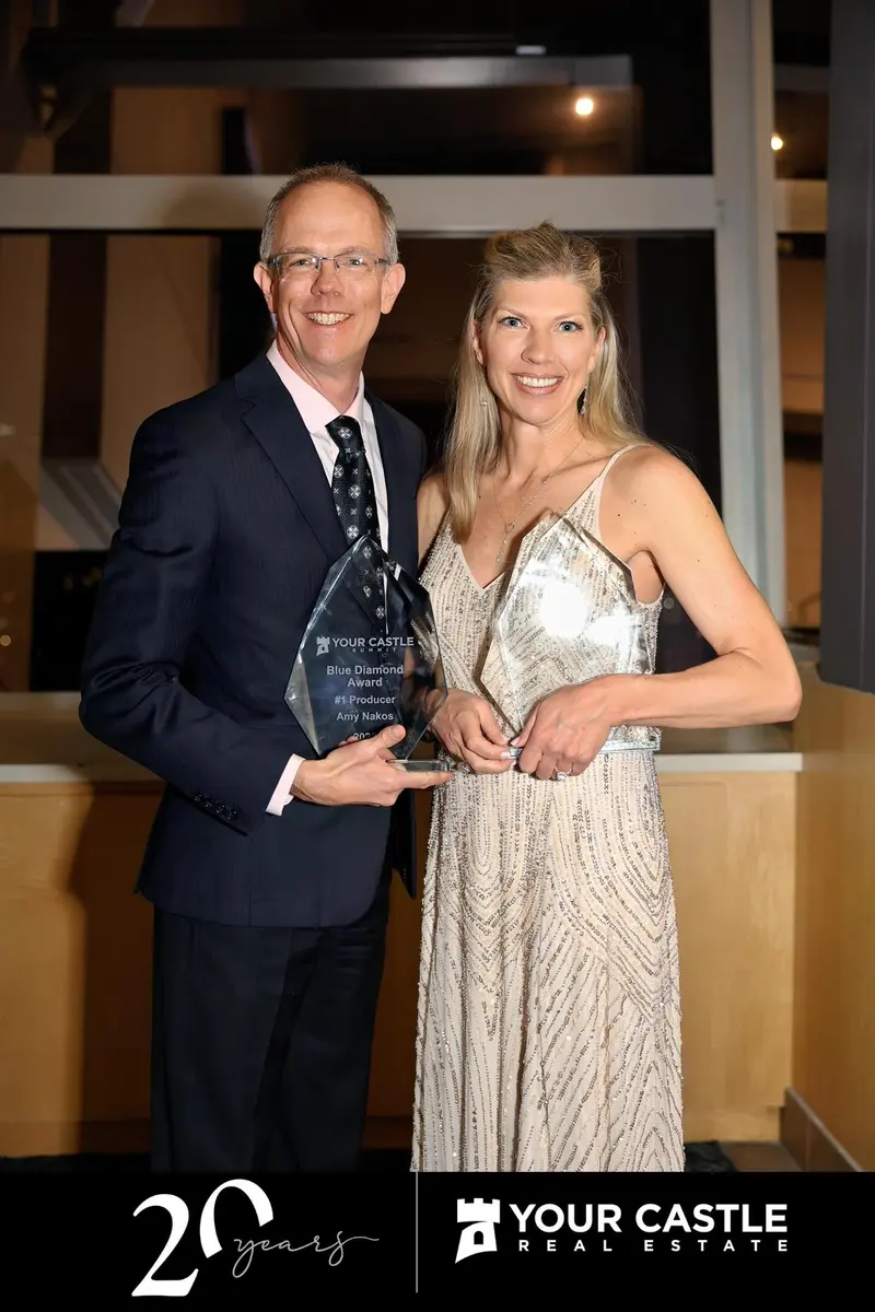Amy Nakos holding a Your Castle Real Estate award at an awards event
