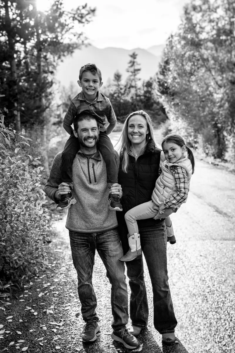 Candice De with her husband and two young children on a tree-lined path
