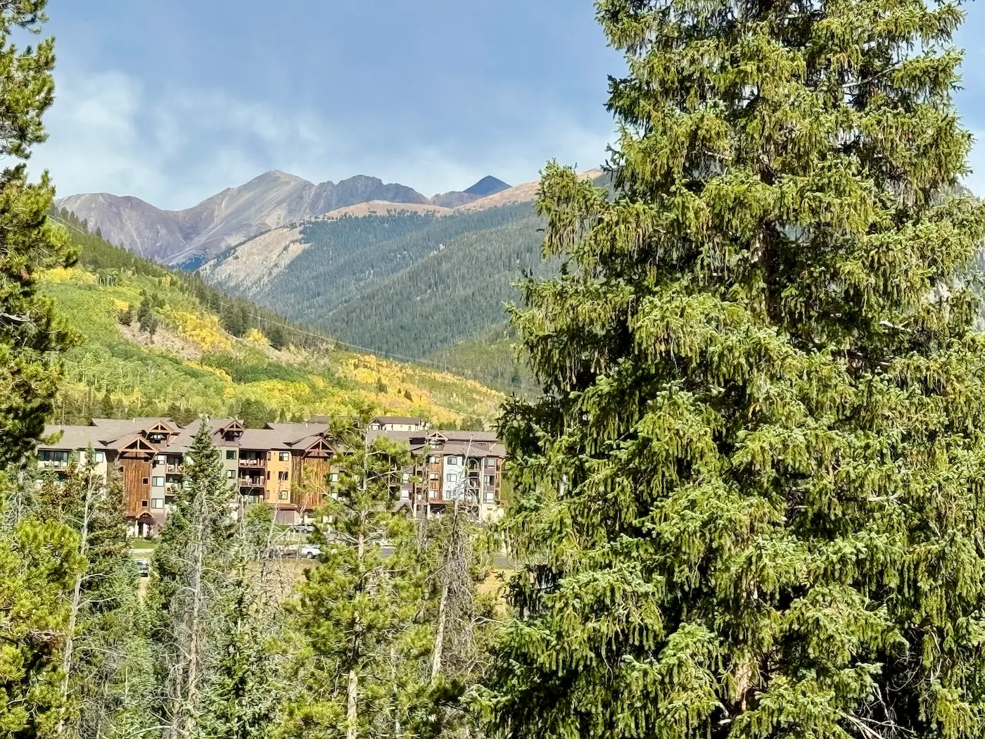 Evergreens and a mountain lodge building in Silverthorne with the Gore Range behind